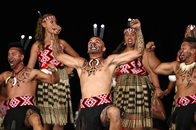 Maori men and women performing the famous war dance; the Haka