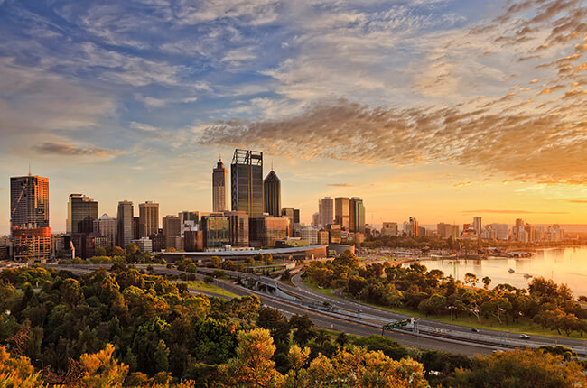 Scenic view of Perth, with autumn colours in the dense tree line - sunset reflecting in the skyscrapers